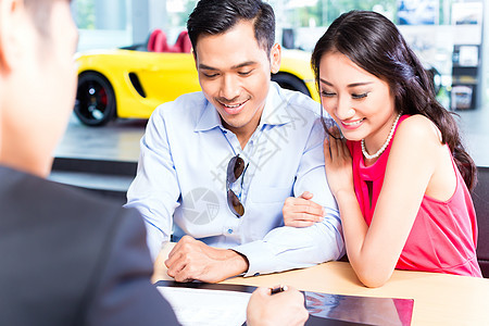 亚洲夫妇签署经销商汽车销售合同的亚洲夫妇租赁陈列室办公室男人顾客女士夫妻交易保险客户图片