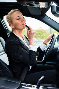 妇女驾驶汽车时使用口红套装人士旅行司机商务商业生意人化妆品镜子图片