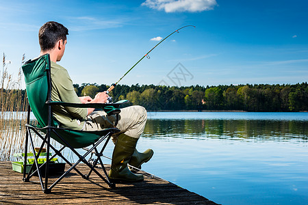 坐在码头的湖边捕鱼的人渔夫钓竿垂钓者运动椅子闲暇娱乐凳子男人爱好图片