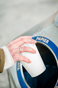 妇女利用垃圾处理容器丢弃咖啡杯使用废物分离集装箱扔弃咖啡杯女性塑料垃圾桶城市平台垃圾分类火车站图片