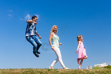 妈妈和女儿在单文件里走着 跳着跳着童年草地后代快乐父亲旅行喜悦父母公园跳跃图片