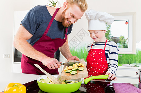 父亲和儿子一起在厨房准备饭菜菜刀油炸蔬菜食物男人孩子们孩子饭厅木板砧板图片