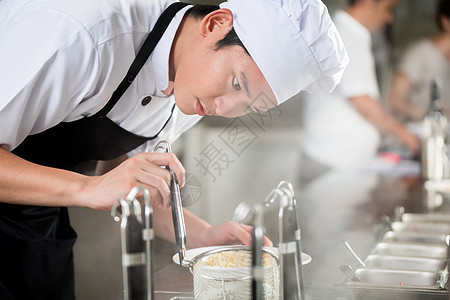 年青亚洲厨师在一家餐馆里做饭图片