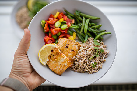 手持鲑鱼和青豆小麦菜健康饮食食谱柠檬午餐盘子蔬菜沙拉食物生活方式服务图片