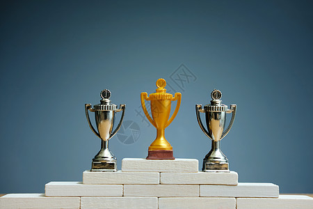 金色勋章站在白色 podiu 上的金色和银色奖杯背景