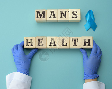 木制立方体 上面刻有男人的健康和一位戴蓝色手套的医生的两只手 及时诊断男性前列腺癌的概念背景