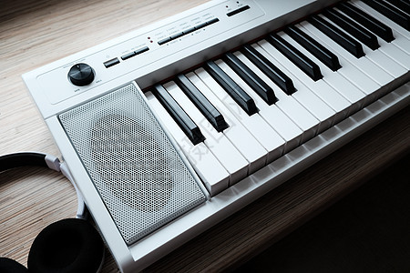 木制桌子上带耳机的白色音乐键盘图片