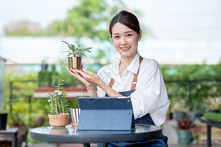 美丽的亚洲女孩拿着植物产品 微笑着向镜头展示 可持续的小型企业工作涉及工厂概念图片