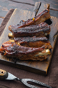 烧烤猪肉备用肋排 木制餐板 用烧烤刀和肉叉 旧黑木桌底图片