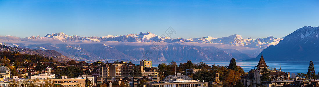 洛桑市风景与日内瓦湖(Lake Leman)的天空全景以及雪将法国阿尔卑斯山在阳光明媚的秋天以蓝云为背景汇集在一起 瑞士沃州Va图片