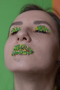 年轻女子肖像 配有糖果化妆品  多彩的糕点 在嘴唇和眼皮上贴珍珠 绿色和橙色的背景 复活节主题口红食物焦点女孩选择性橙子图片