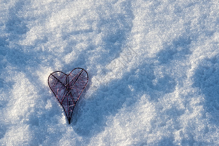 躺在雪地里的金属粉红心 上面有横幅或背景的副本图片
