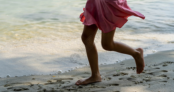 一个女童沿着河岸奔跑 用脚溅水 夏天 孩子在沙滩上玩耍 赤脚在沙滩上奔跑 海游 孩子们的脚在沙子里背景图片