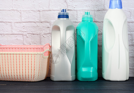 在木制蓝色桌子上装有液体洗涤剂和塑料空洗衣篮的瓶子凝胶卫生肥皂盒子白色家务粉色清洁工化学品家庭图片