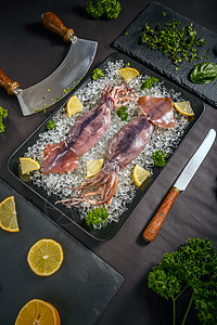 新鲜切塔特鱼美食鱿鱼动物章鱼墨水柠檬海鲜食物盘子黑色背景图片
