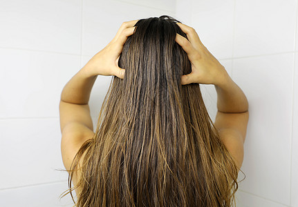 年轻女人用指头涂发油 洗头发前擦头发 理发概念图片