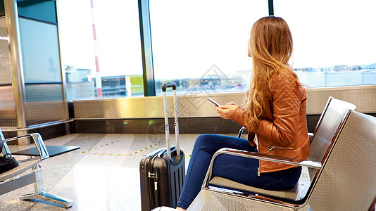 美丽的年轻女子在机场休息室等待登机时 仰视着飞机飞行的窗外女青年图片