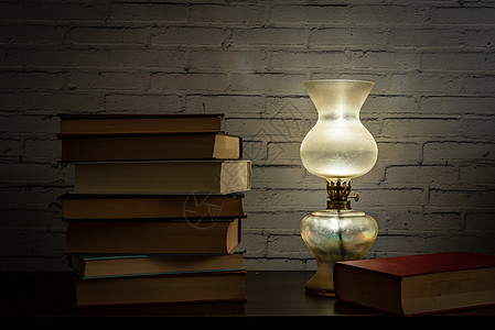 书籍装帧油灯光照亮了暗木头表面的书本背景