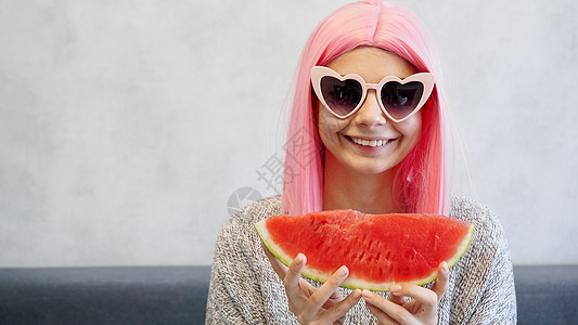 女人戴着粉红色假发和心形眼镜 穿着粉色假发太阳水果海滩食物乐趣牛仔裤西瓜饮食配饰产品图片