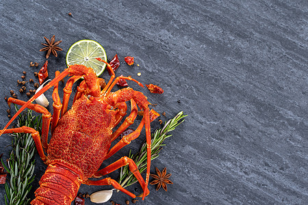 煮熟的龙虾 美味的晚餐海鲜餐 黑色石板背景上配有刀叉 餐厅菜单设计 顶视图 头顶柠檬盘子桌子食谱食物动物贝类香料石头美食图片