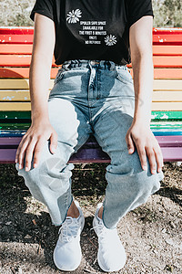 近身穿着妈妈牛仔裤的女人 在公园的彩虹长椅上重量男朋友孩子们爸爸父亲服装标签男生腰部靴子图片
