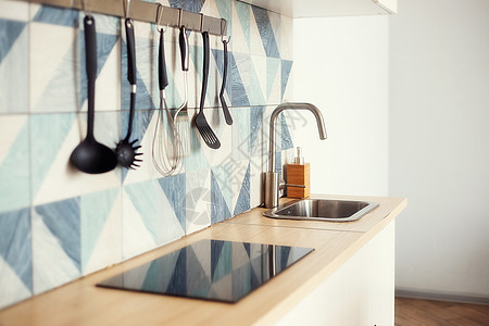 用蓝色几何图案在砖墙上竖起栏杆的厨房式弹簧管柜台房间厨具厨房家庭勺子架子家居水平用具图片