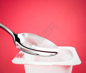 红底面的酸果杯和银勺子 含酸奶霜的白色塑料容器 用于健康饮食和营养平衡的新鲜奶制品乳糖营养牛奶生物饮食奶油茶点食物产品杯子图片
