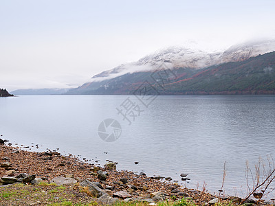 苏格兰希格兰沉暗日落前的山丘湖 在镜水上方有雪色山锥野性河岸海浪石头高地下雨天气树干爬坡季节图片