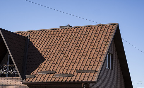 安装在现代房屋上的棕色波纹金属型材屋顶 波纹板屋顶 金属型材波浪形屋顶 现代屋顶由金属制成 金属屋面房子窗户山墙聚合物建造建筑建图片