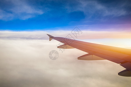 飞行和旅行 在日落时间从机翼上的飞机窗口查看 在地球和云层下的飞机机翼 在天空中飞行 看着飞行中的飞机机翼机器货物地平线阳光蓝色图片