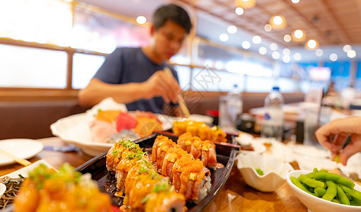 日本餐厅有选择地专注于日本料理 三文鱼寿司在盘子里 模糊的男人在餐厅里用筷子吃日本菜 健康的亚洲食品 三文鱼寿司菜单食物午餐派对图片