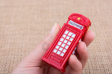 英国电话亭手持一个挂在画布背景上的电话亭盒子城市红色公用电话电话帆布亚麻英语背景