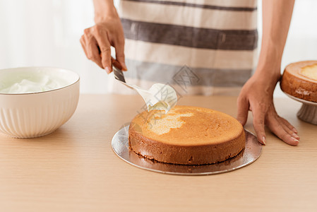 制作海绵饼 手在木桌上新鲜烤蛋糕上加冰淇淋厨房糕点甜点海绵食物女性饼干奶油糊状厨师图片