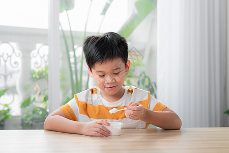 甜美的男孩吃酸奶早餐奶制品营养勺子小吃孩子乐趣食物童年饮食幸福图片