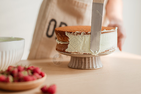 人手水平奶油在蛋糕上 蛋糕装饰 做海绵蛋糕过程红色鞭打木头烹饪脆皮男性厨师面包白色覆盆子图片