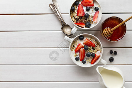 美味多彩的早餐 包括燕麦片 酸奶 草莓 蓝莓 蜂蜜和牛奶 白色木制背景 带复制空间 顶视图图片