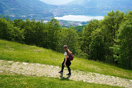 女性远足者走在小径上 从湖的山顶以满意的方式寻找图片