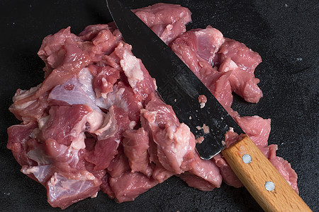 在特写镜头中用刀将猪肉或牛肉切成薄片 肉类菜肴和食品的准备 烤羊肉串 烧烤或烤肉串用的红肉片 用刀切生鲜肉 食谱用具木板饮食餐厅图片