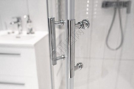 玻璃浴门的铬手柄贴近了 现代浴室的内部图片