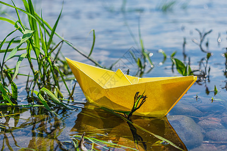 黄纸船停在草地上河岸附近图片