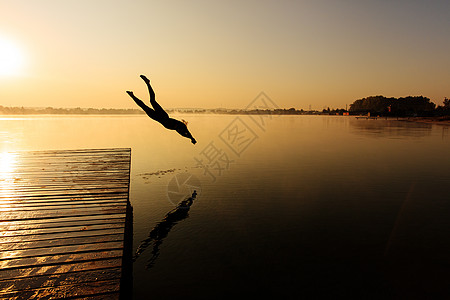 活跃男子从雾密湖的木码头跳跃图片
