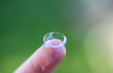 在绿色夏季自然背景模糊的指尖上用透明隐形透视镜光学近视手指矫正验光师保健镜片角膜卫生眼睛图片