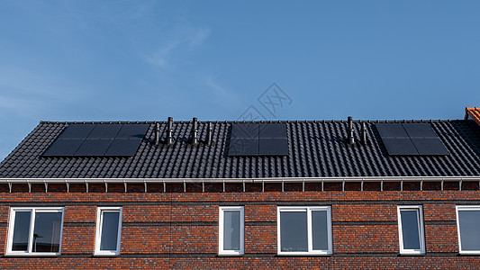 在阳光明媚的天空下 屋顶上附有太阳能电池板的新建房屋特写带有黑色太阳能电池板的新建筑 翻译 太阳能电池板 太阳能环境电气绿色生态图片