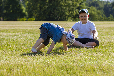 开朗的孩子们 两兄弟 开心地笑着 我们很高兴在温暖晴朗的天气里在公园的草坪上散步和玩耍 孩子们的情绪在脸上震惊金发女郎童年青年快图片