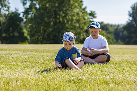 开朗的孩子们 两兄弟 开心地笑着 我们很高兴在温暖晴朗的天气里在公园的草坪上散步和玩耍 孩子们的情绪在脸上头发男生学校乐趣青年兄图片