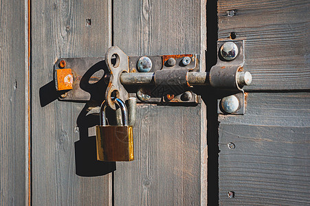 新的闪亮的黄铜挂锁 花园木棚门有锁建筑安全钥匙金属坚果房子保险灰色木头图片