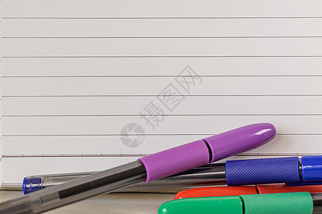多种组合的办公文具照片带钢笔铅笔记事本笔记本尺订书机剪刀剪纸回形针夹夹板放在桌子上文档工具办公室书写创造力紫色木头圆珠笔蓝色材料图片