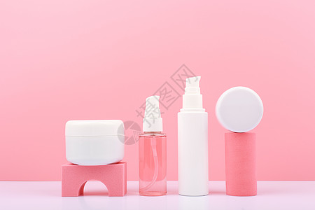 一套装有美容品的化妆瓶 以粉红背景为几何道具奶油讲台皮肤护理香脂洗剂管子精华擦洗瓶子图片
