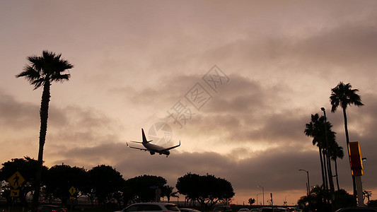 飞机在日落时降落在美国加利福尼亚州洛杉矶的机场 客机或货机剪影 戏剧性的云景 飞机抵达机场 国际运输飞行图片