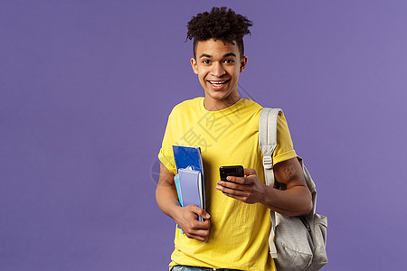 号码头回到学校 大学的概念 年轻英俊微笑男子的肖像 学生要求同学电话号码 在手机上做笔记 背着背包 拿着笔记本和学习材料套装培训班微笑背景